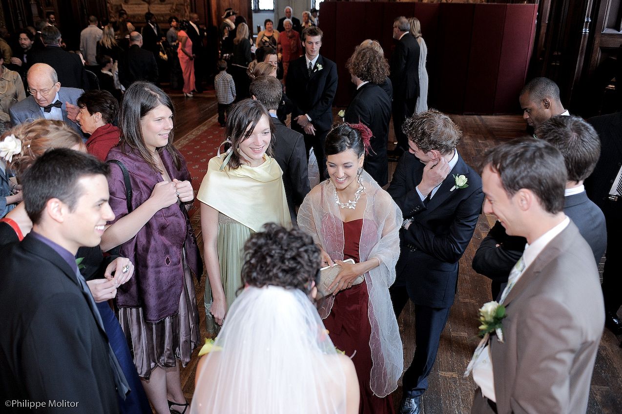 Wedding guests gathered in an elegant venue, socializing in formal attire during a reception celebration.