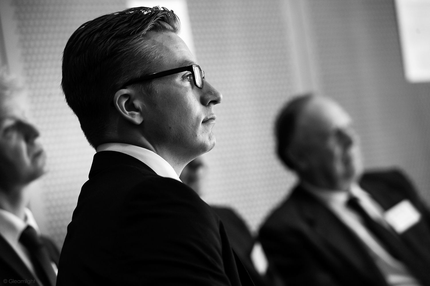 Silhouetted profiles of people seated in a dark conference setting.