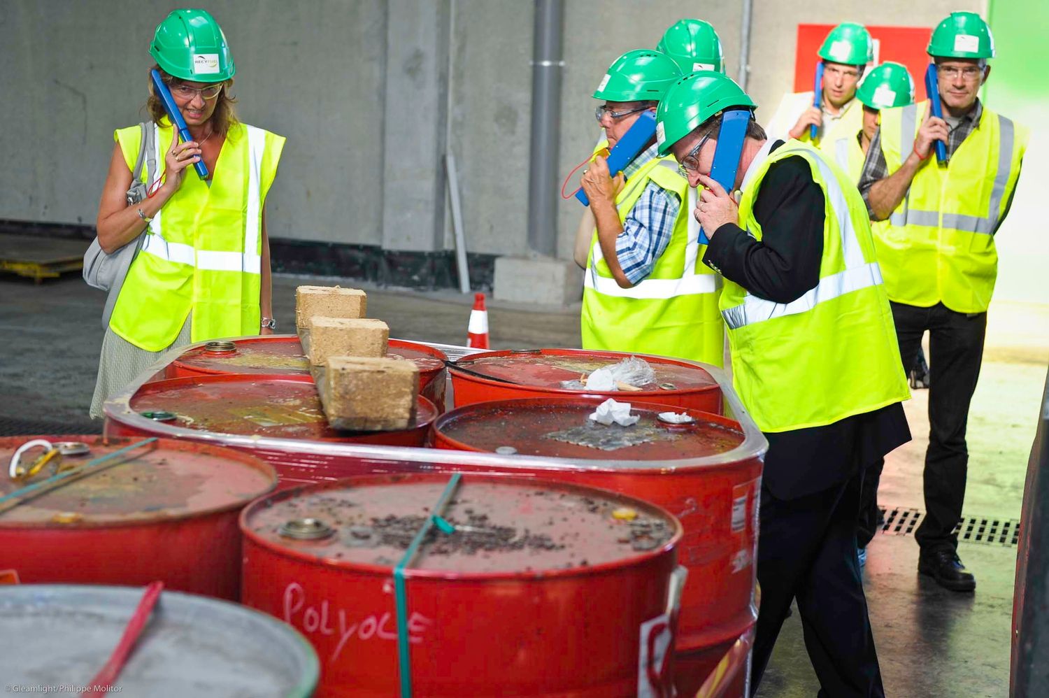 Construction workers in safety gear gathered around red industrial equipment.
