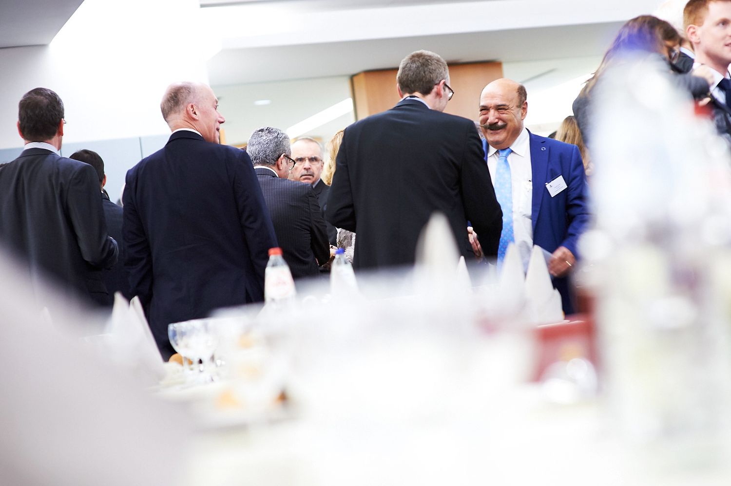 Business professionals engaged in conversation during a networking event in a bright indoor space.