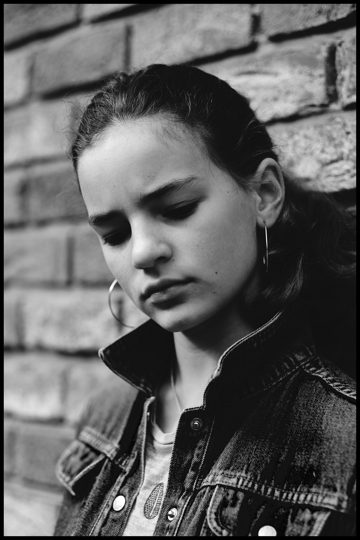 Black and white portraits against brick wall with moody lighting and leather jacket.