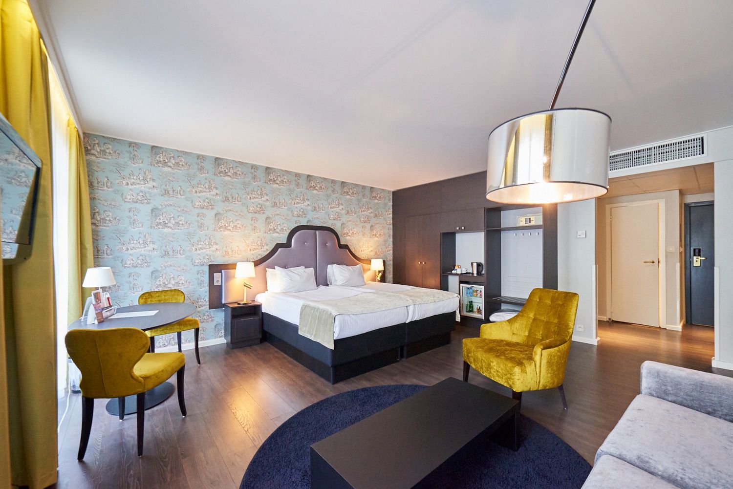Hotel room interior featuring yellow chairs and exposed brick wall details.