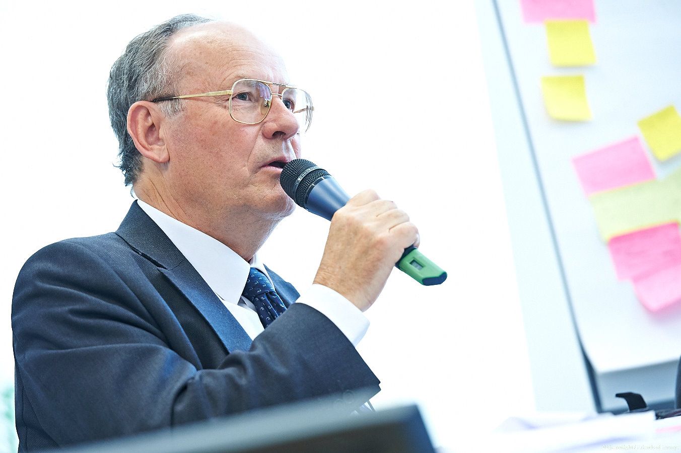 Business presentation with sticky notes visible on wall during corporate strategy session.
