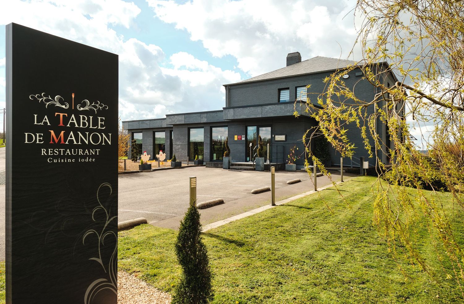 Modern restaurant exterior with black signage against a cloudy sky.