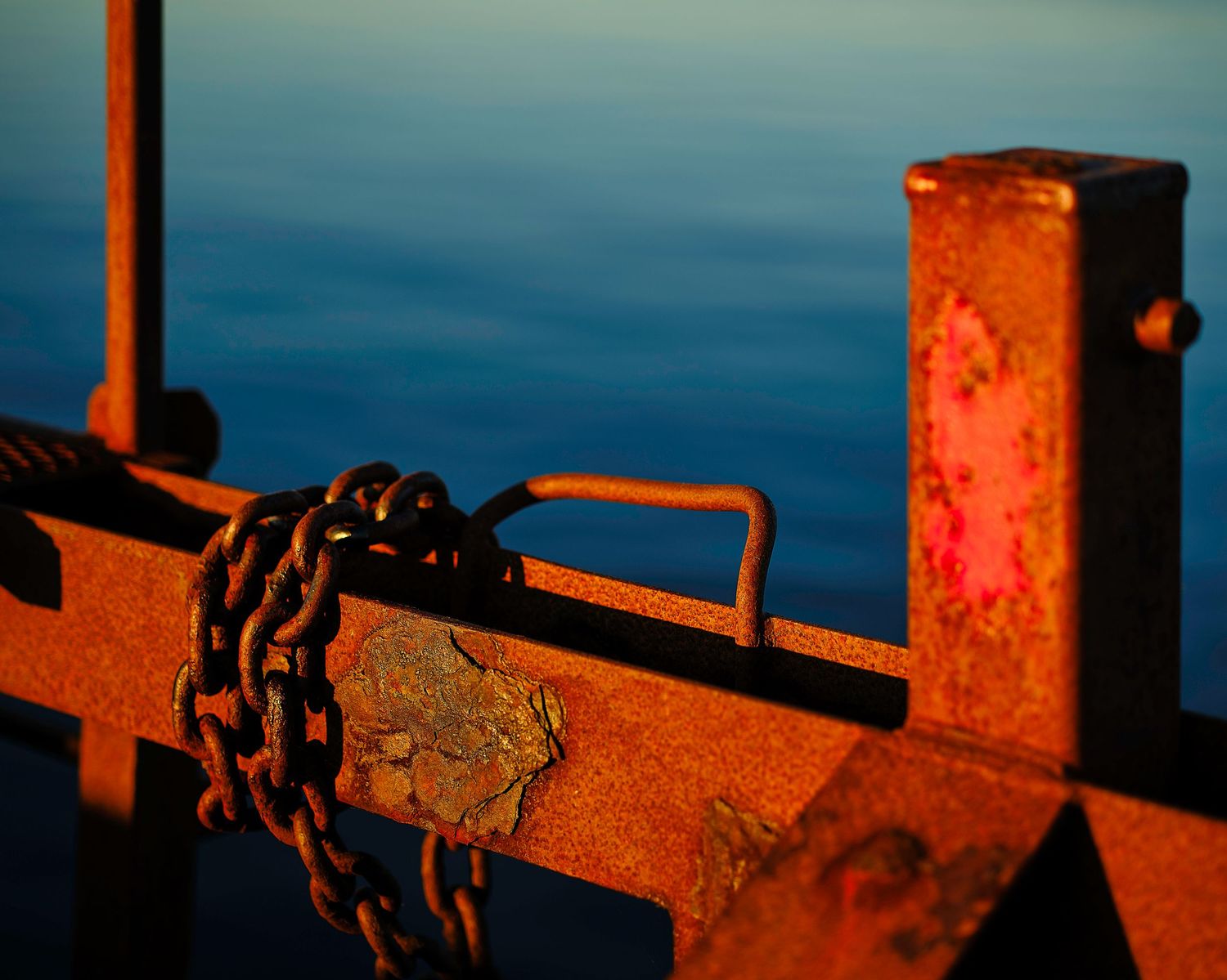 Industrial metal structures casting orange shadows during golden hour against dark blue background.