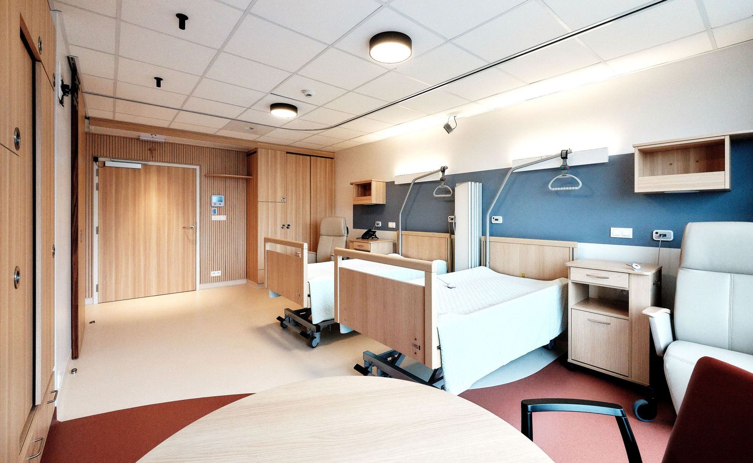Modern medical facility room with adjustable bed and monitoring equipment.