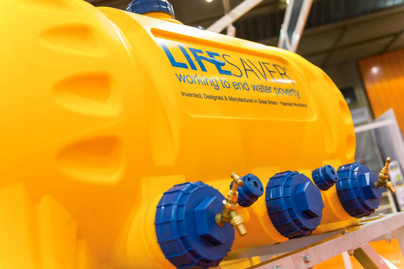 Row of yellow and blue industrial equipment or containers displayed on a shelf.