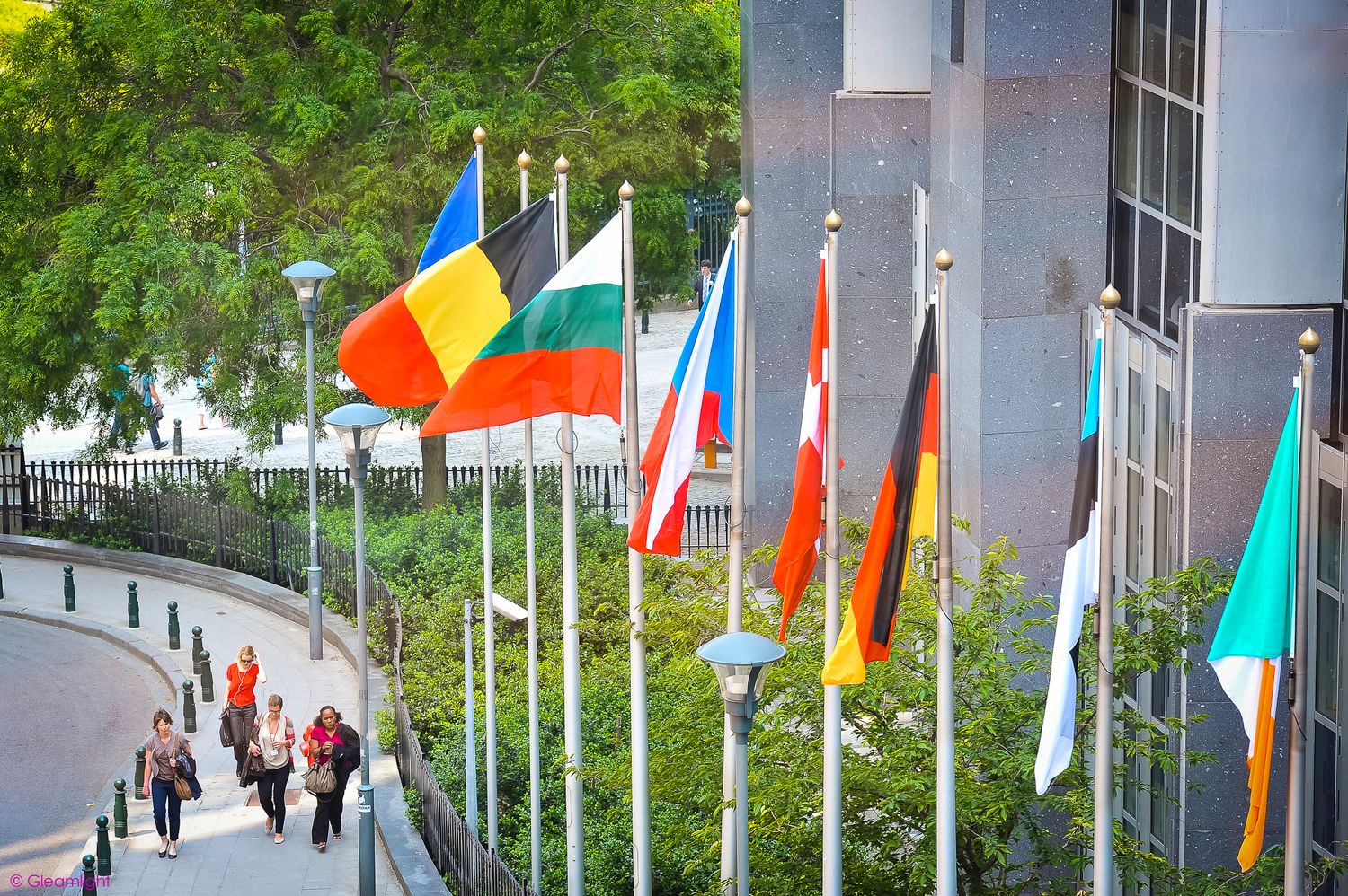 International flags waving along a curved path outside a building.