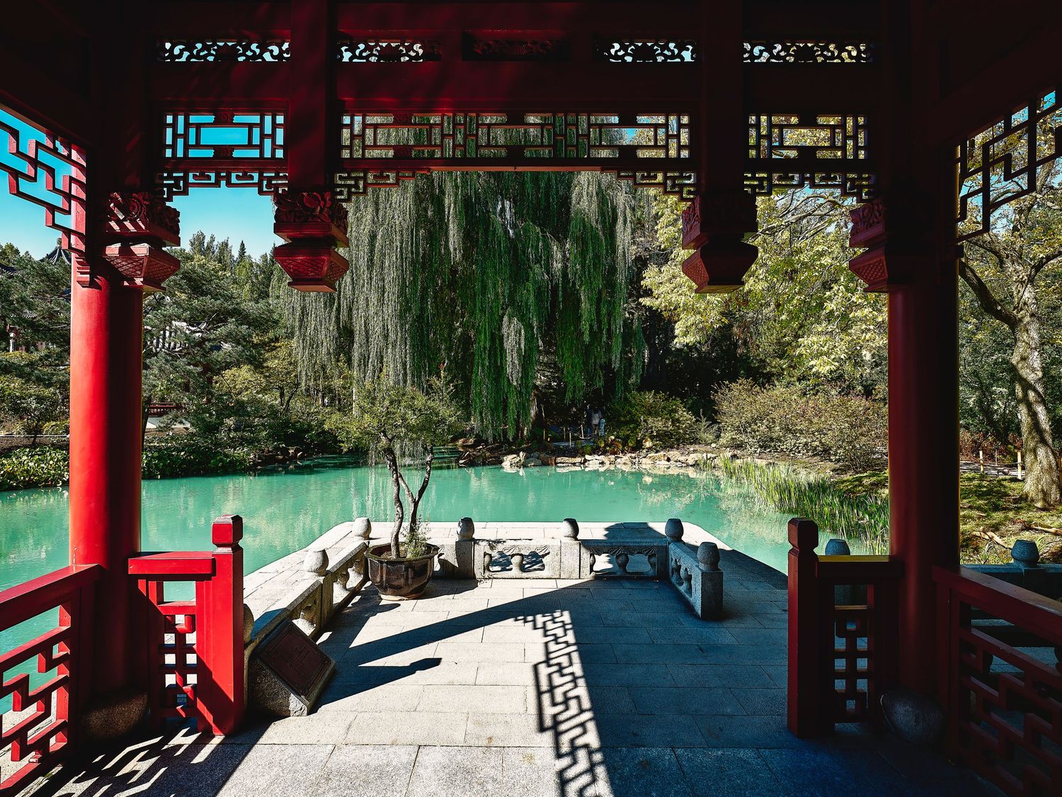 Traditional Chinese garden pavilion with red pillars and ornate decorative roof details.