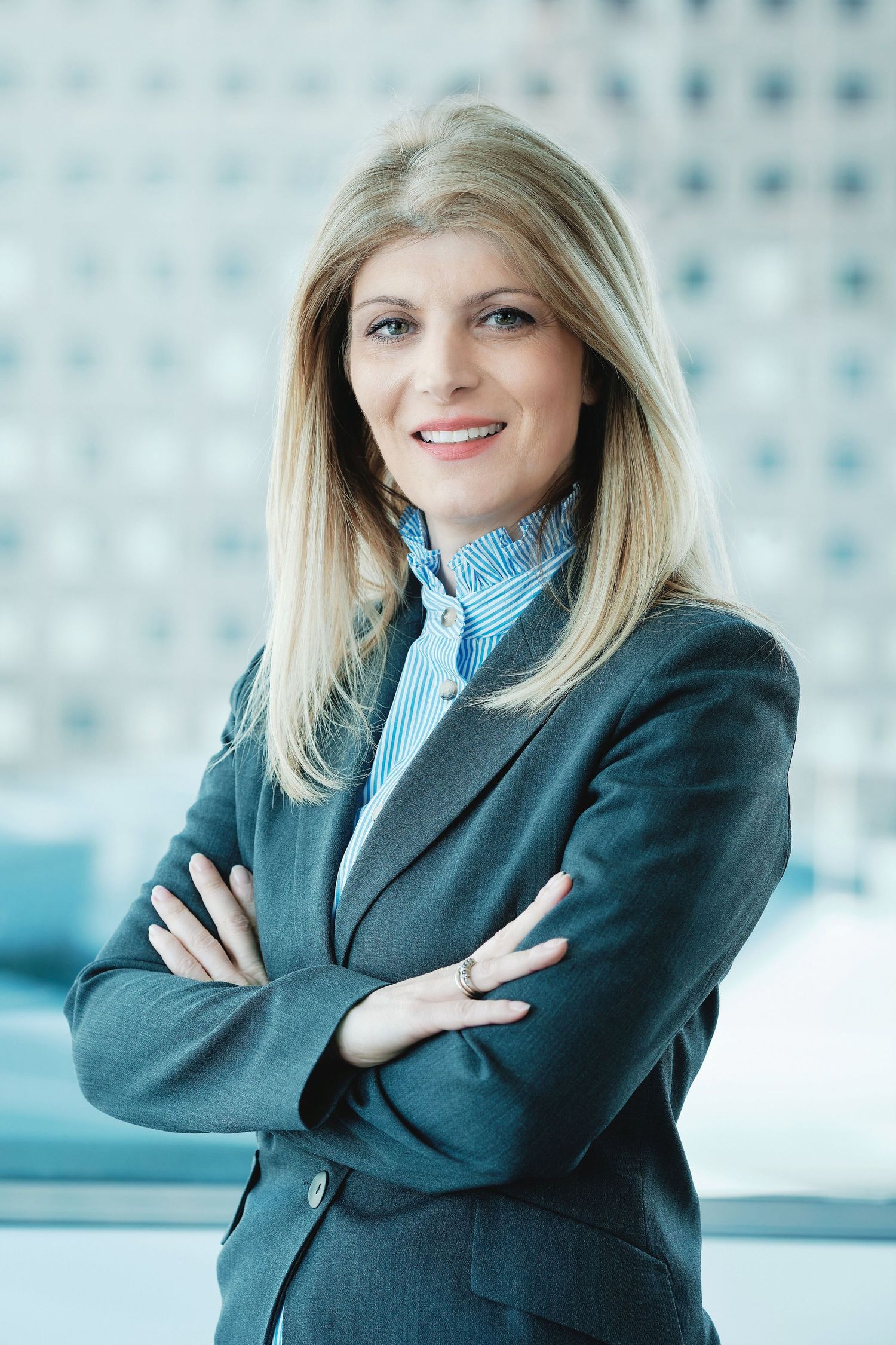 Professional business portrait of a confident executive in a dark blazer against a modern office background.