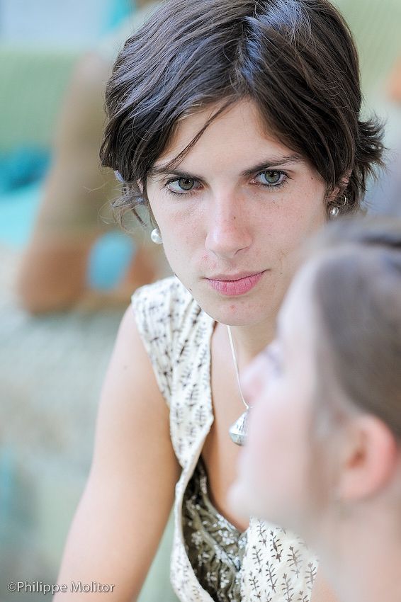 Young woman with short dark hair and green eyes wearing a floral dress and silver necklace.