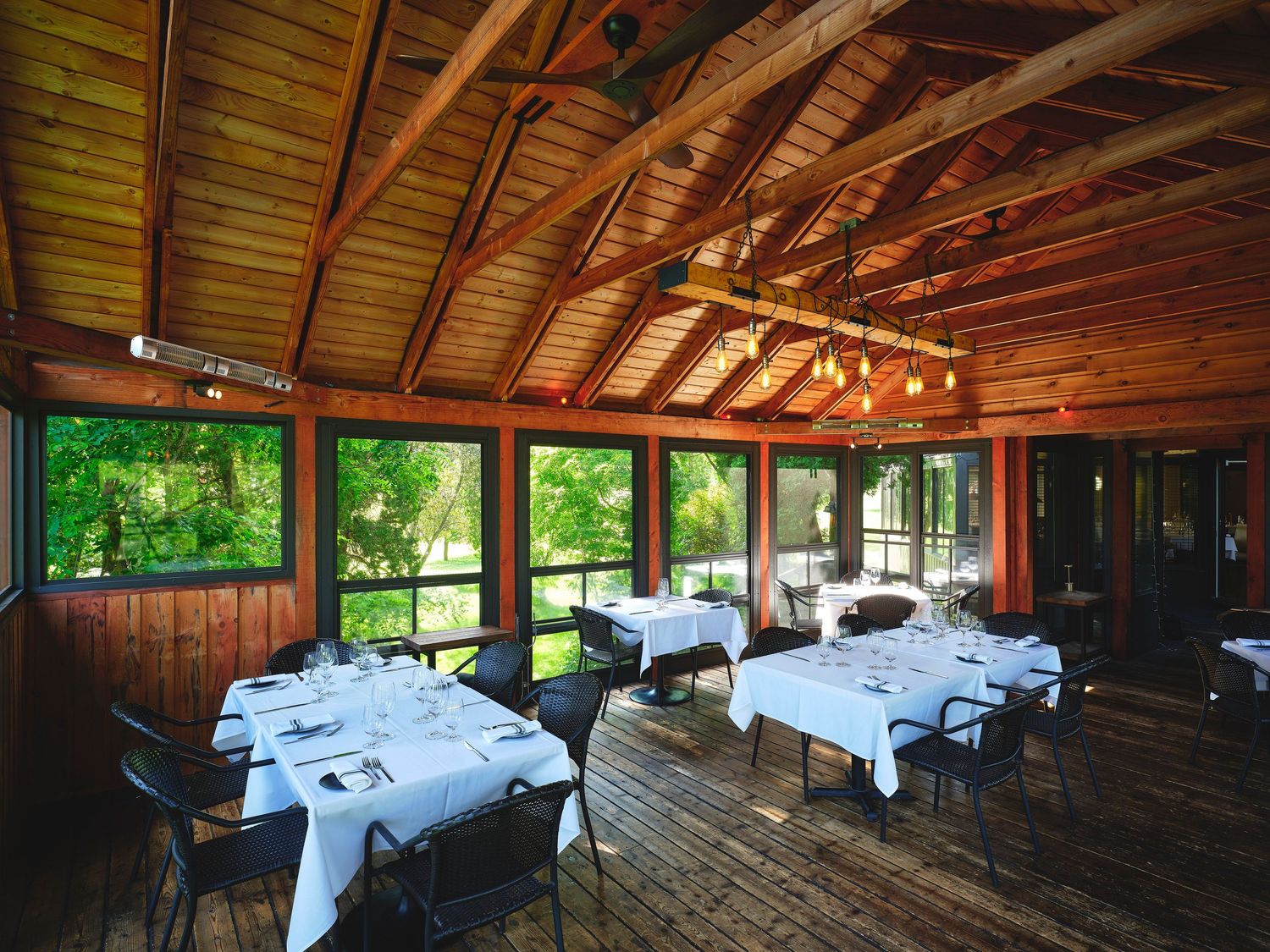 Large wooden event space with vaulted ceilings and white-clothed dining tables set for a formal occasion.