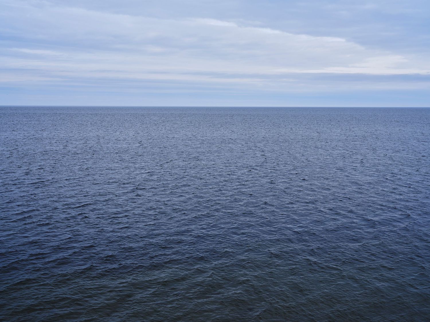 Calm blue ocean horizon stretches endlessly under an overcast sky.