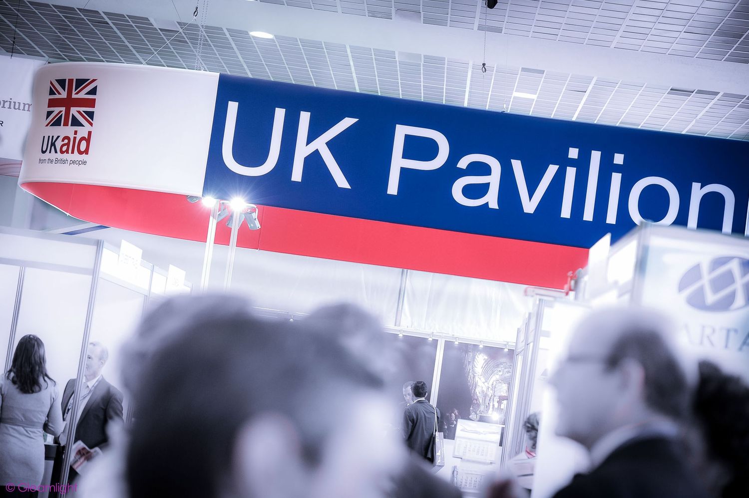 Interior view of a convention center with UK Pavilion signage and flags.