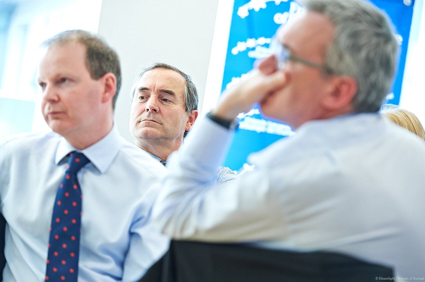 Business professionals in discussion during a corporate meeting with bright lighting.