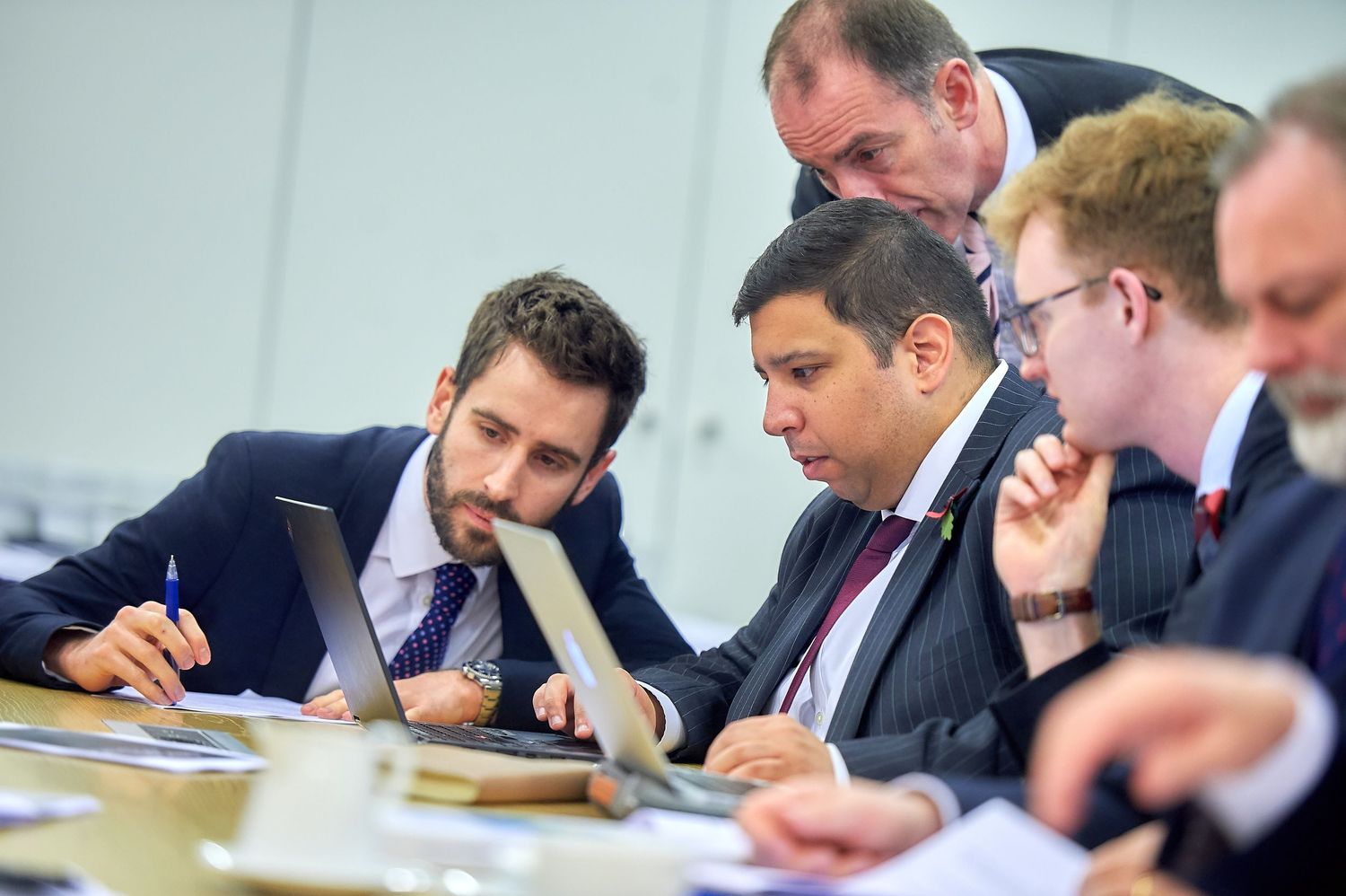 Corporate executives working together reviewing documents at conference table.