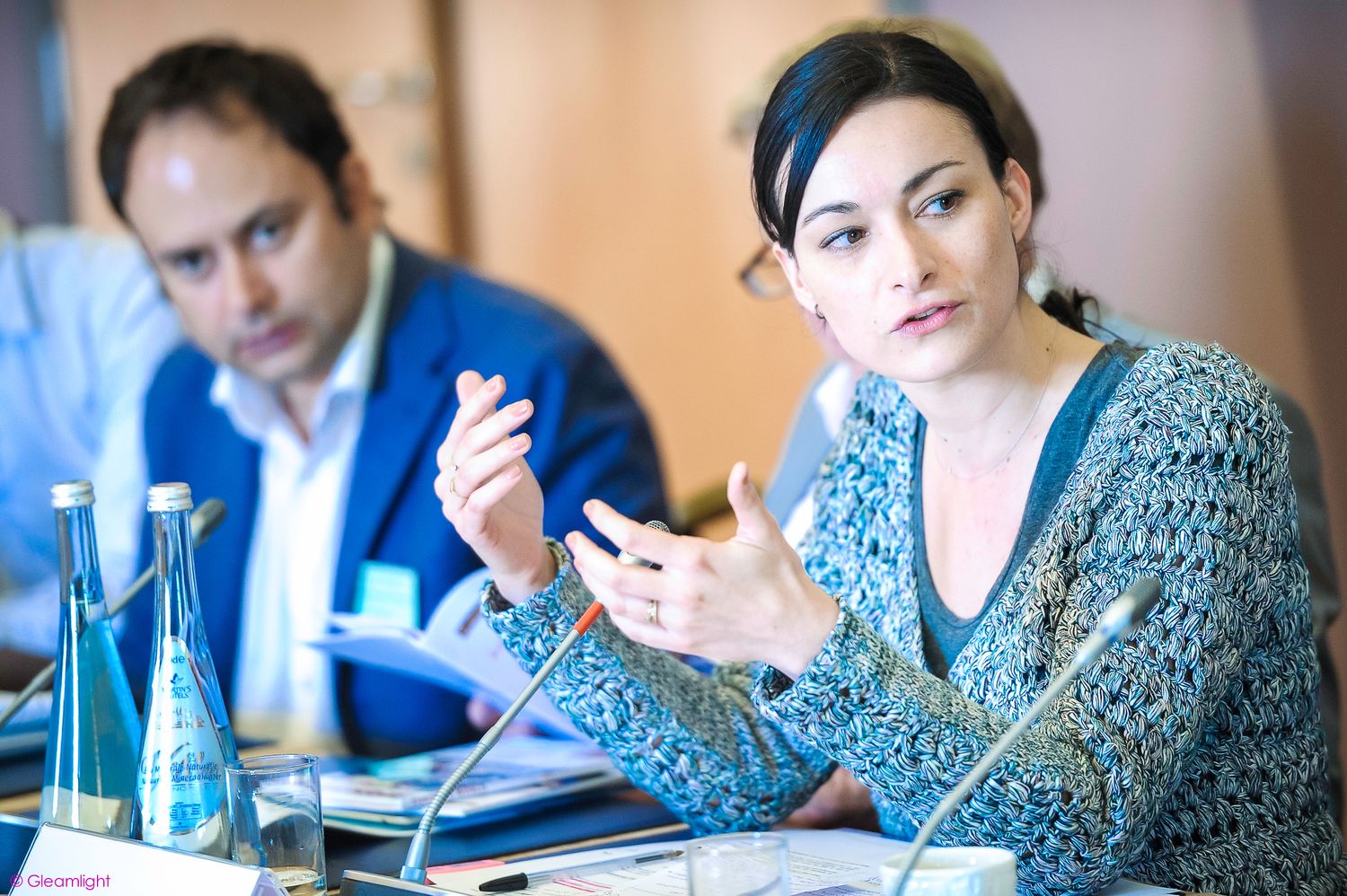 Business professionals engaged in discussion at a conference table with documents and laptops.