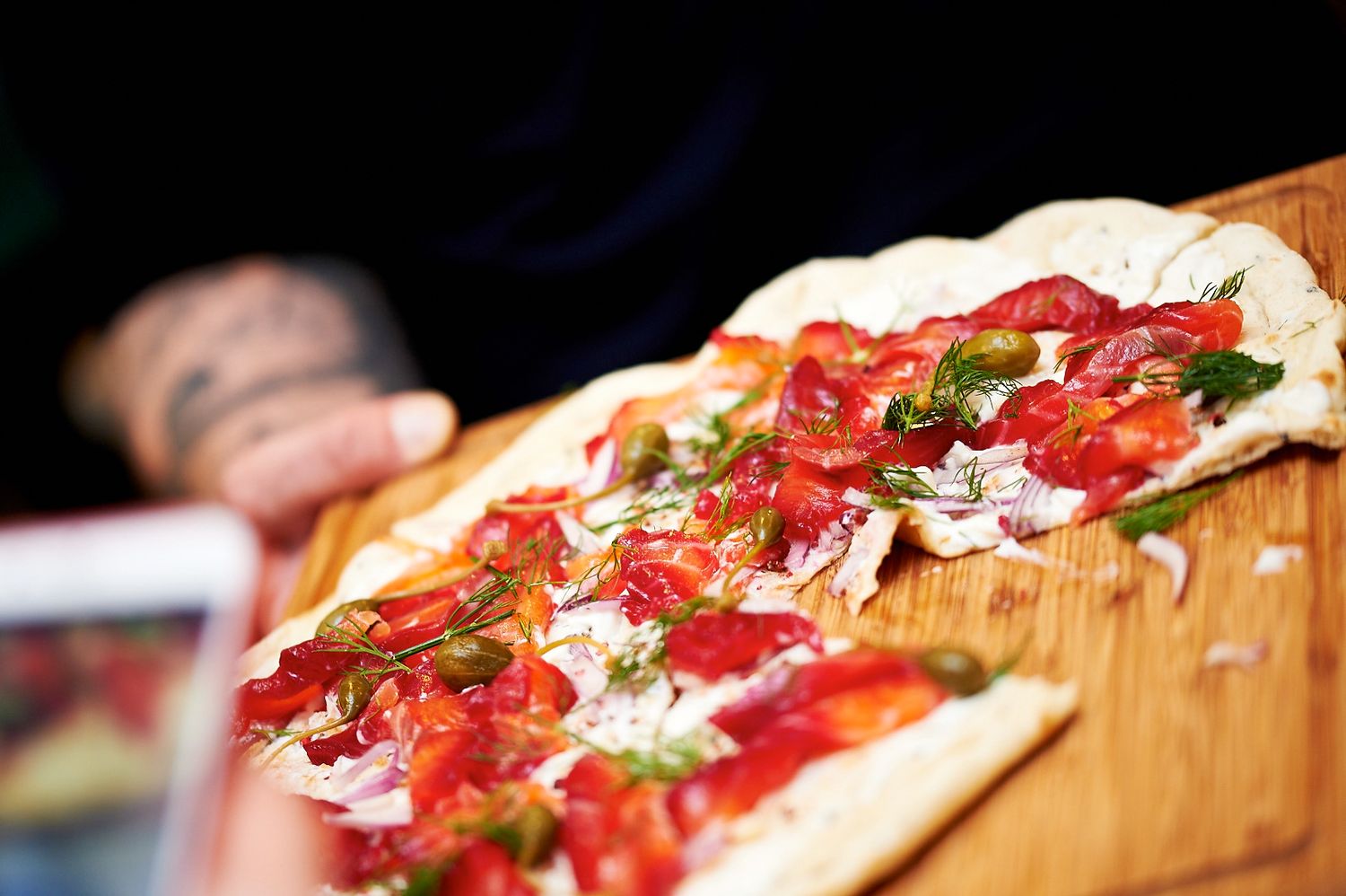 Close-up of a pizza topped with fresh ingredients on a wooden cutting board.