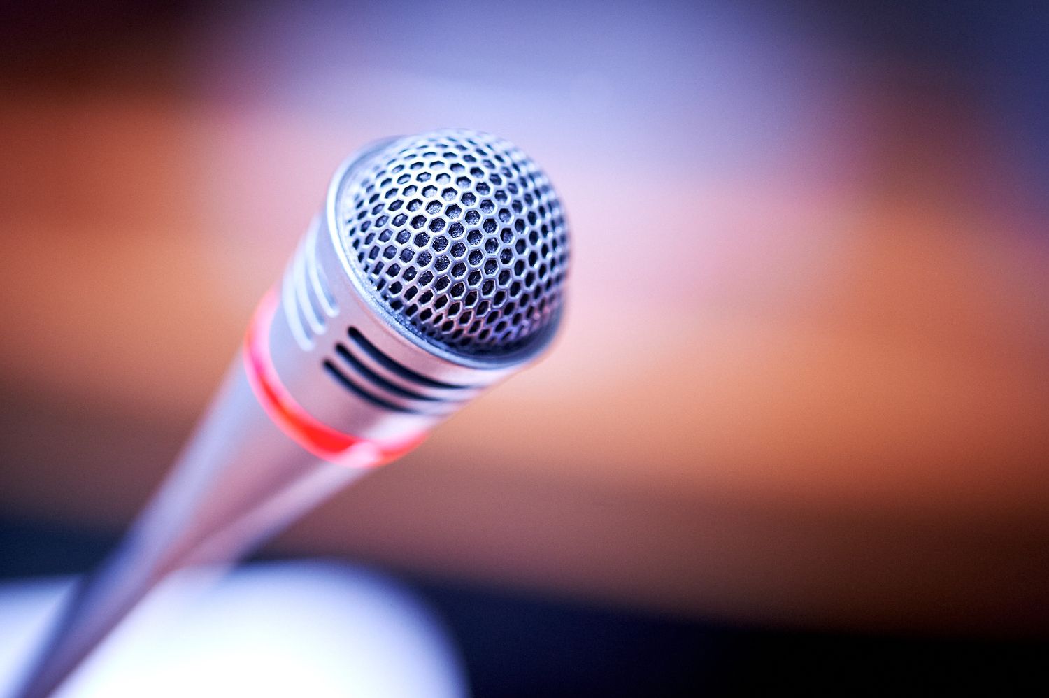 Close-up shot of a professional microphone with blurred warm background.