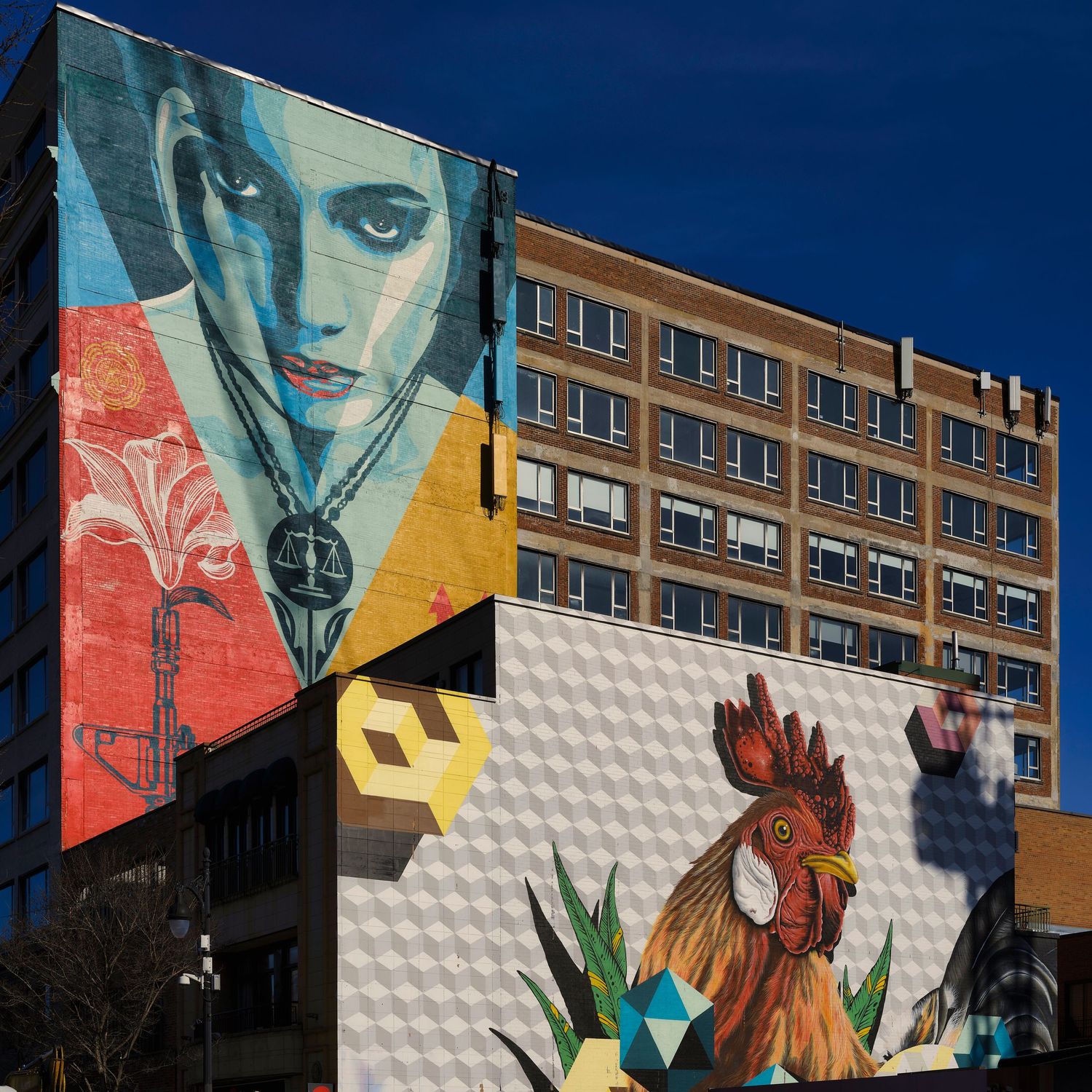 Colorful street art mural featuring a rooster and geometric patterns on the side of an apartment building.