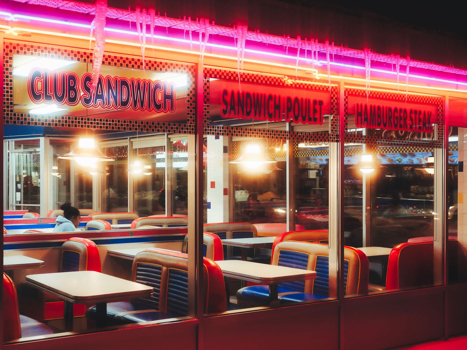 Retro diner exterior with bright neon signs illuminating the night scene.