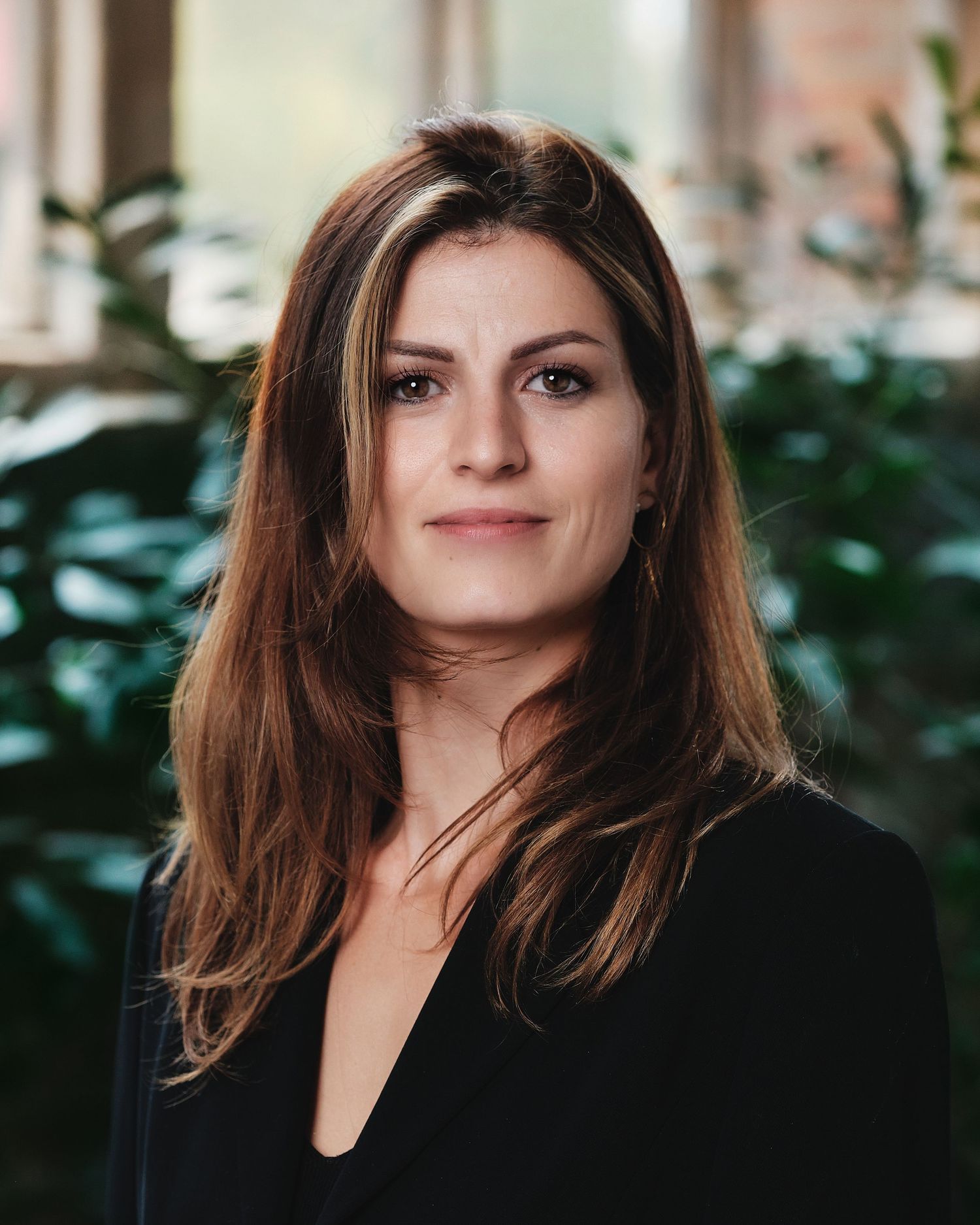 Professional in black business attire photographed against blurred office background.