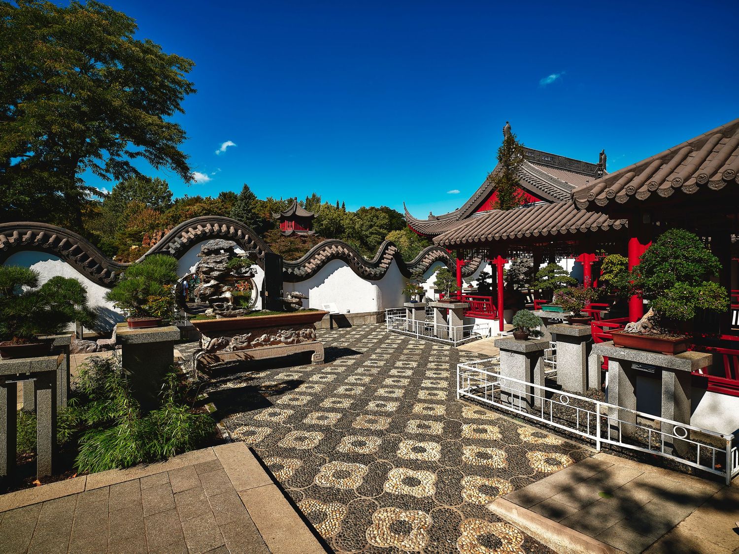 Chinese garden courtyard with traditional architecture and checkered stone pattern flooring.