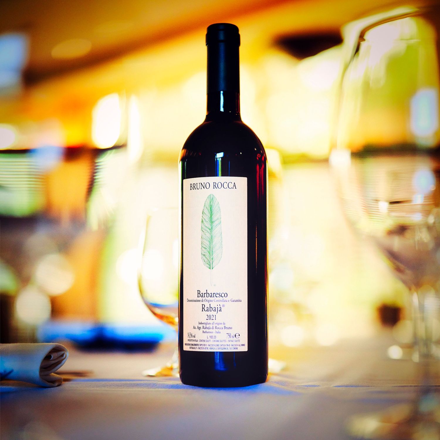 A row of wine bottles and glasses on a wooden table with warm ambient lighting creating a romantic atmosphere.