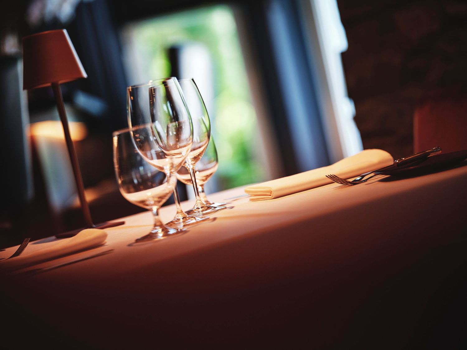 Close-up of an elegant table setting with wine glasses in warm ambient lighting.