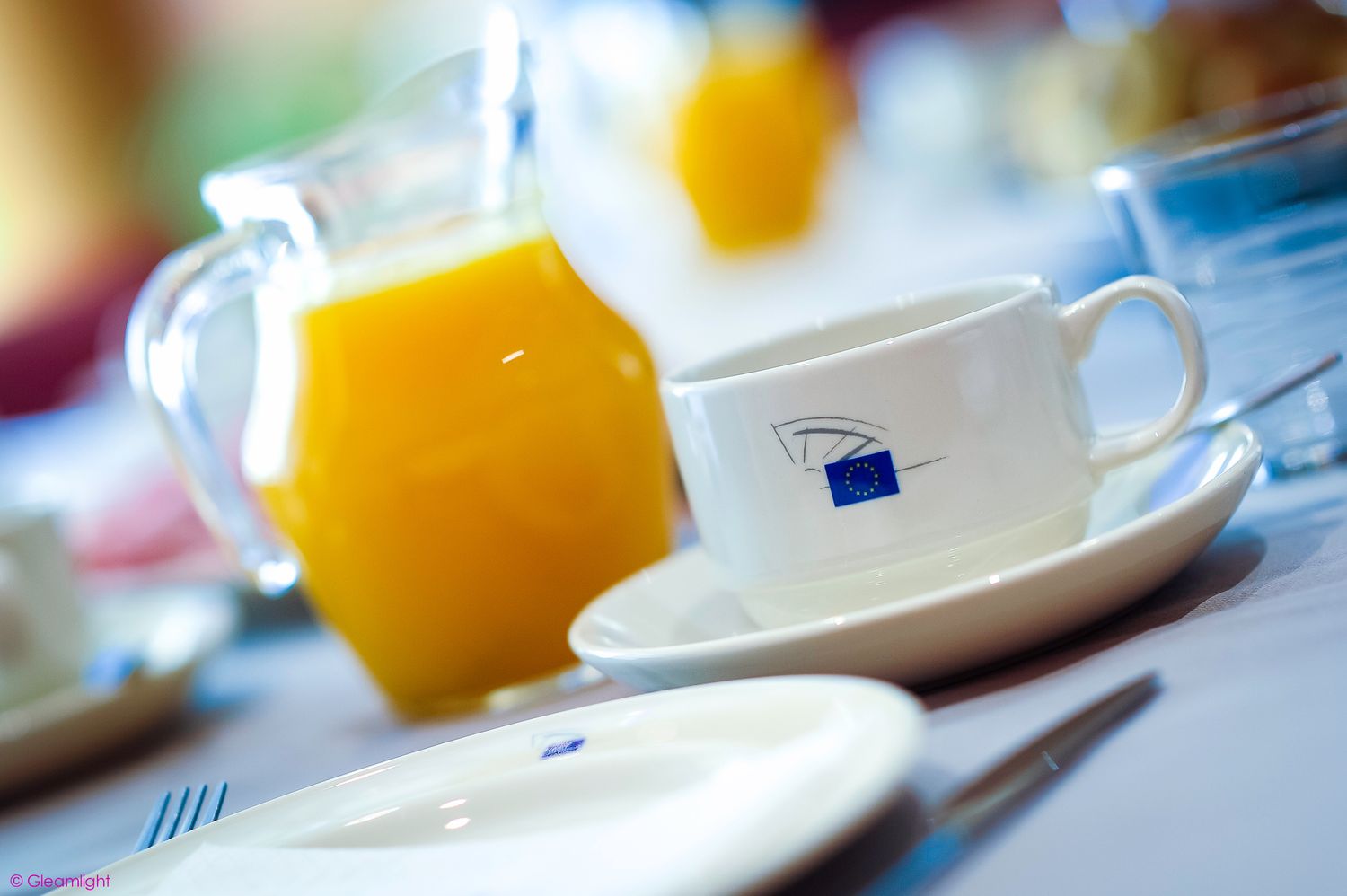 Close-up of breakfast settings with orange juice glasses and plates on a table.