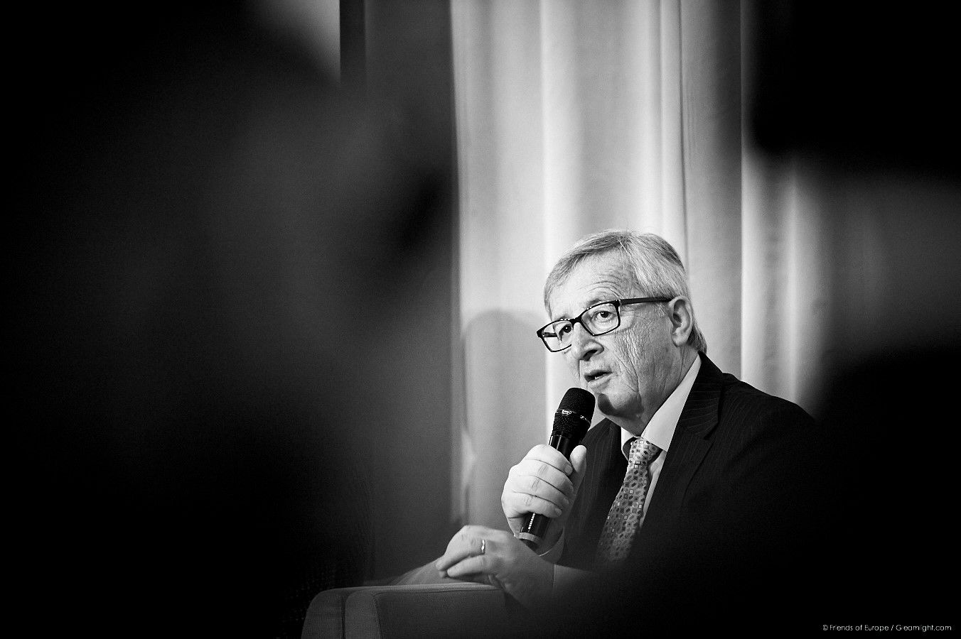 Dramatic black and white portrait shot of a speaker at a podium.
