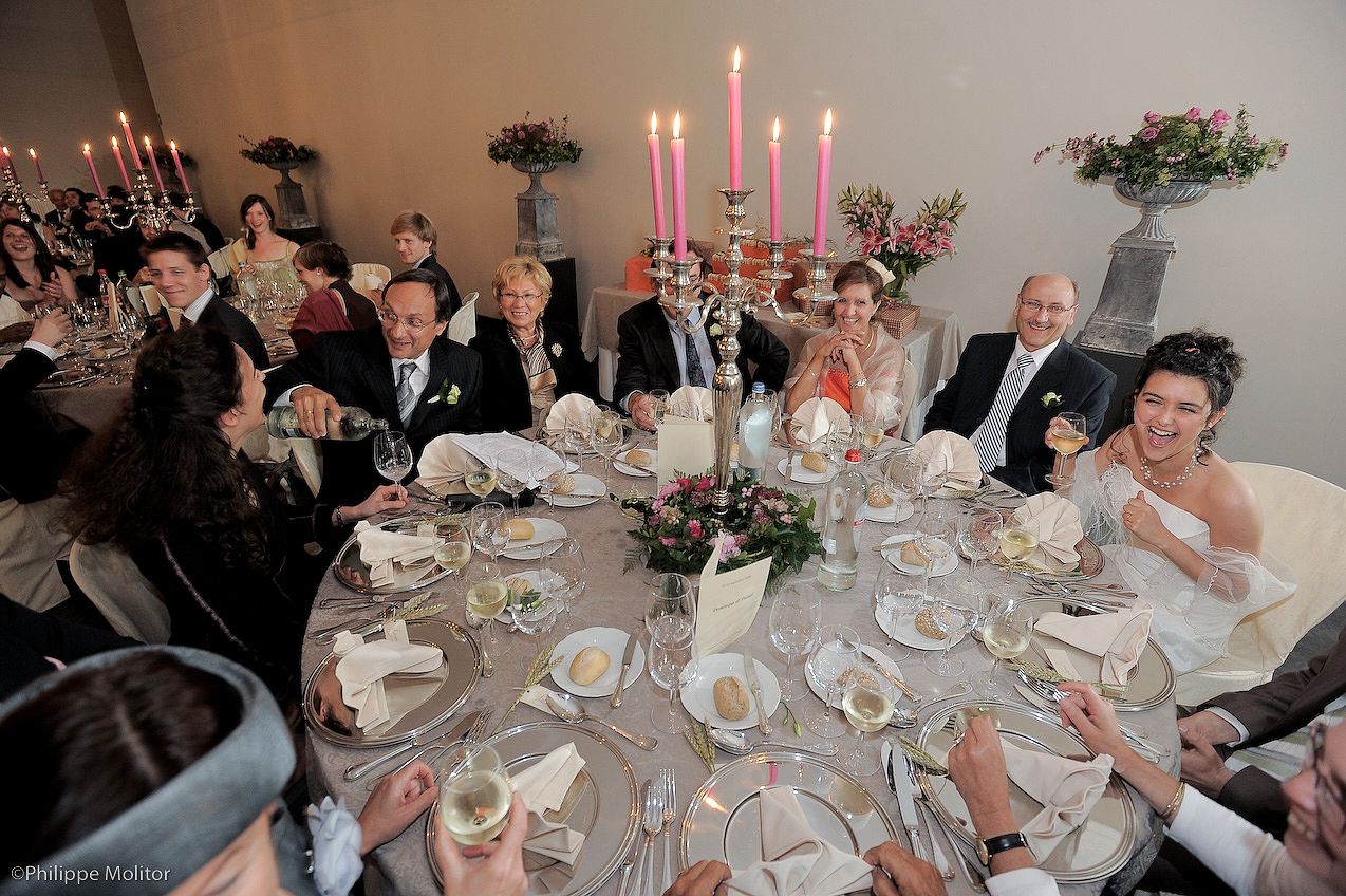 Wedding reception dinner with bride and groom seated at a round table with candelabras and floral centerpiece.
