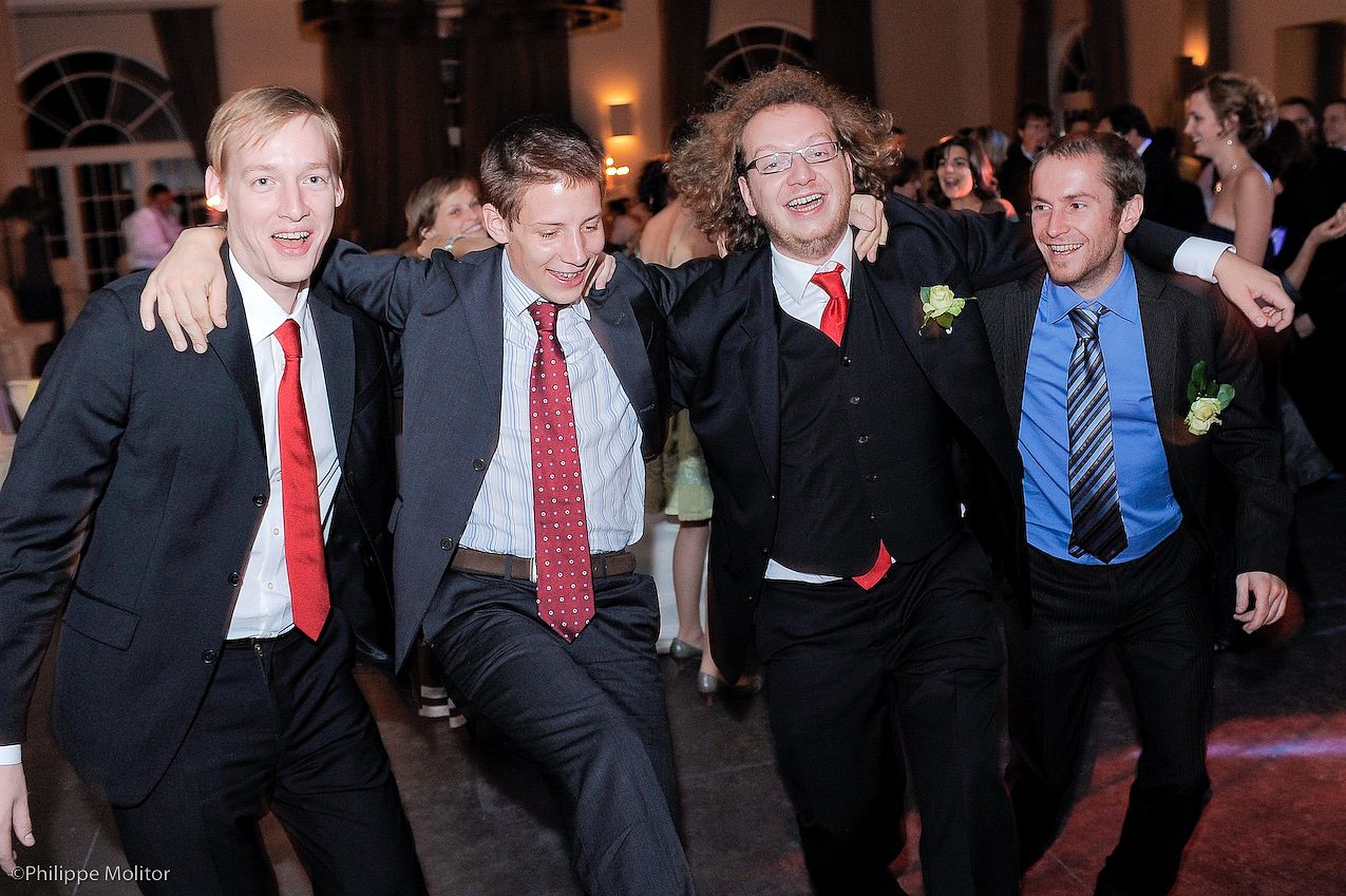 Four young men in suits and ties smile and pose together at a formal event or prom celebration.
