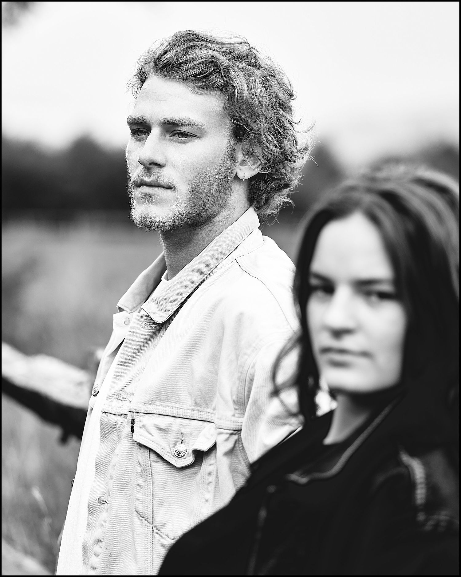 Artistic black and white outdoor portrait of two people in contrasting light and dark clothing.