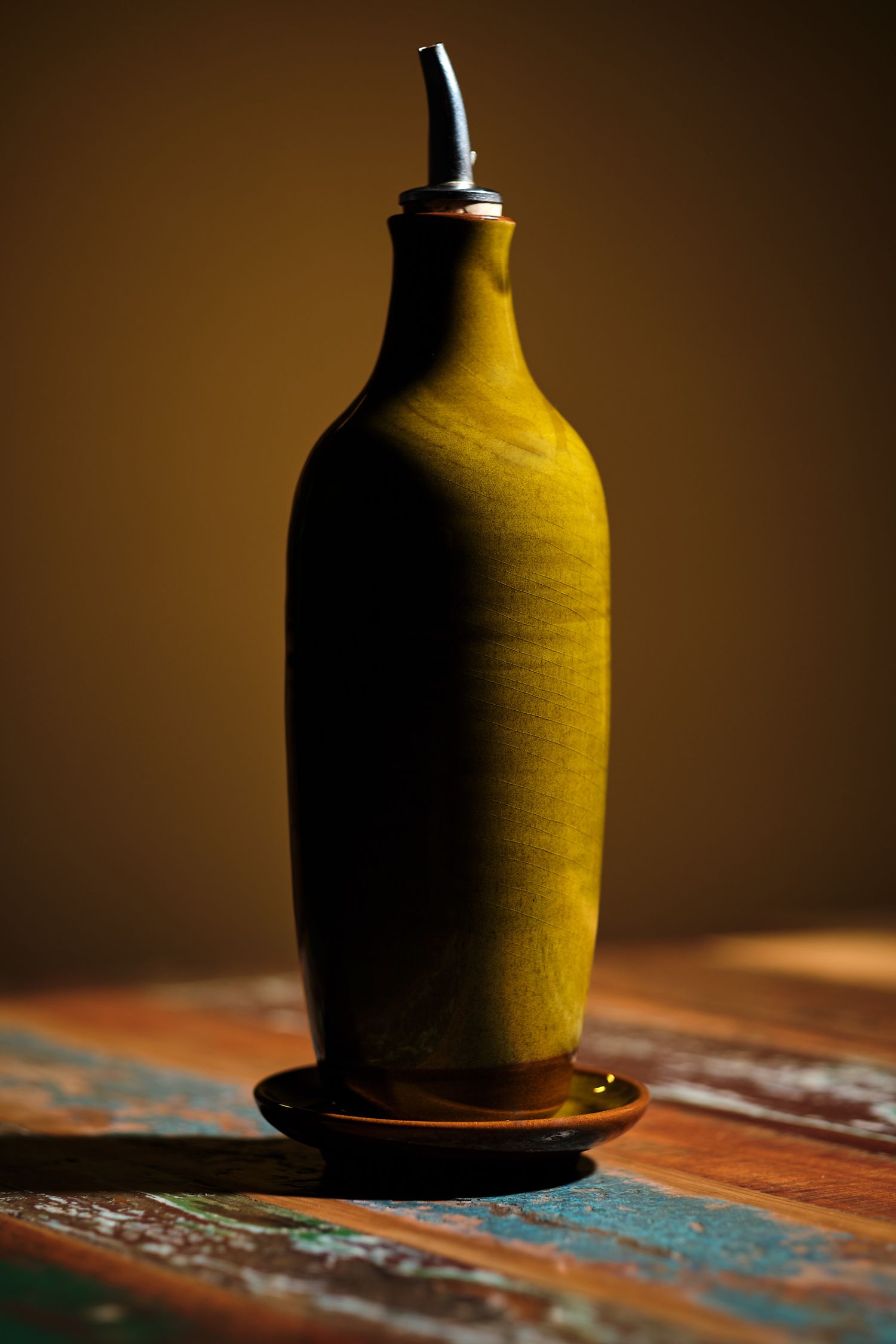 Silhouette of a yellow bottle against a dark brown background on a textured surface.