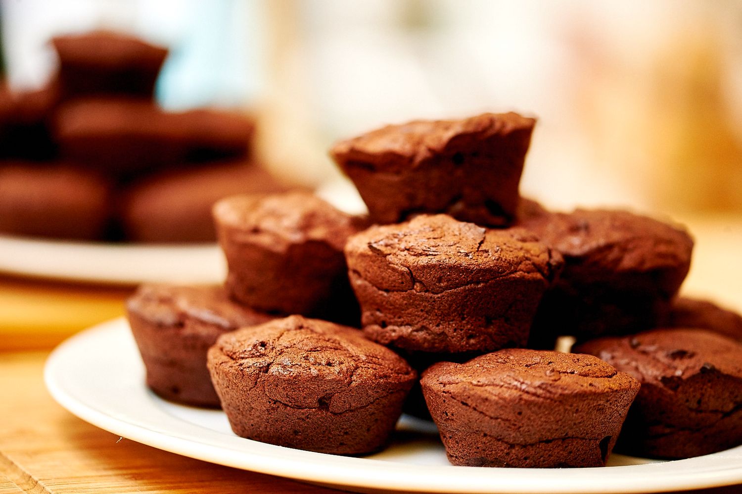 Fresh chocolate muffins arranged on a white plate with a soft focus background.