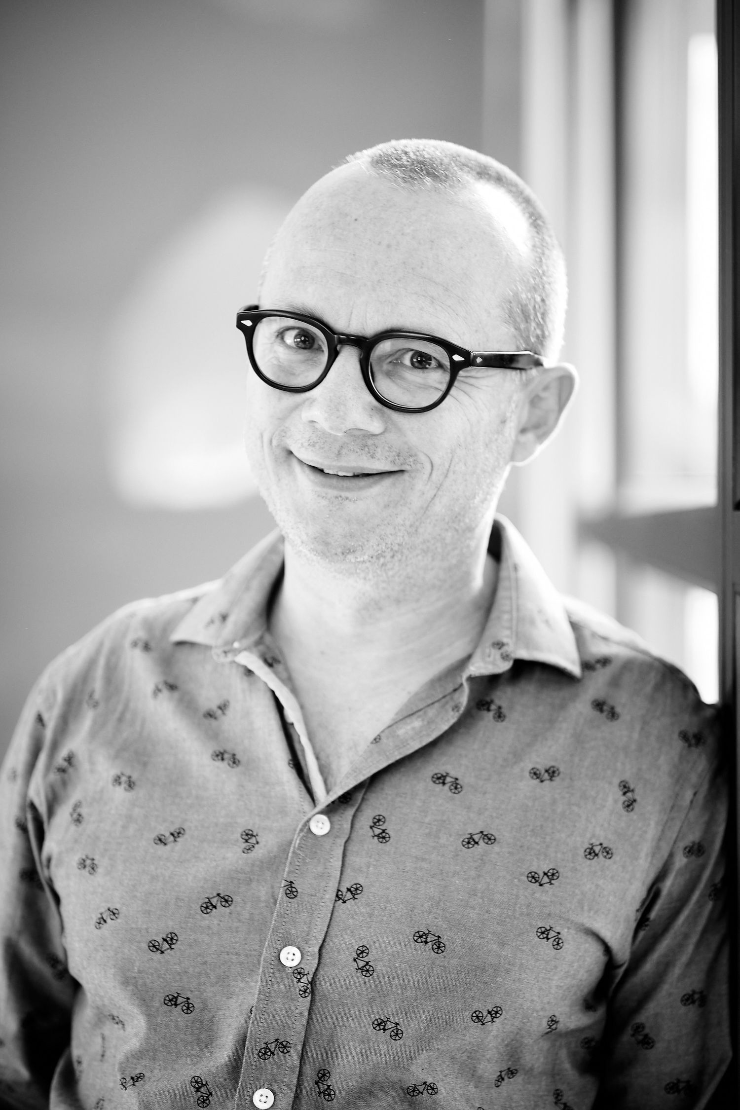 Black and white headshots of person wearing glasses and patterned shirt.