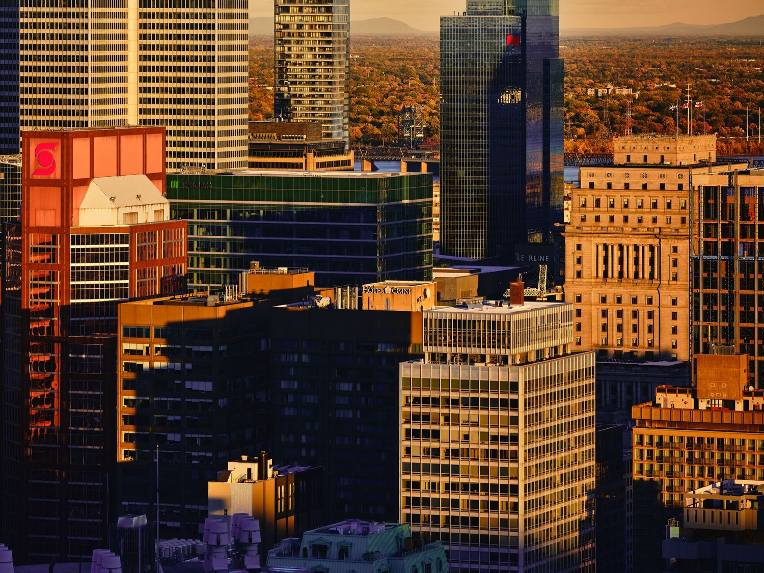 Aerial cityscape view of downtown Portland Oregon at sunset with modern skyscrapers and mountain backdrop.