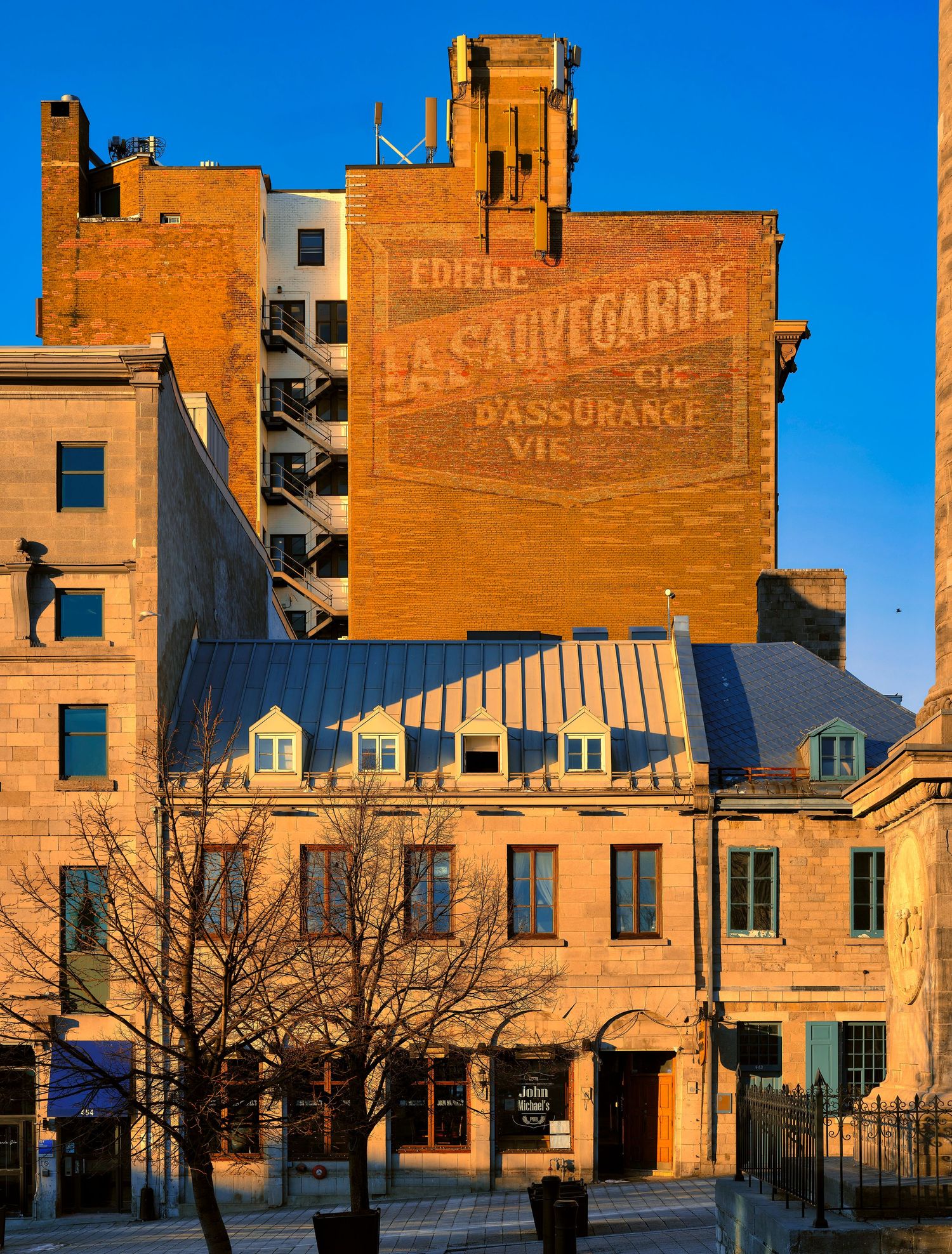 Vintage brick buildings with faded painted advertisements illuminated by golden sunlight against a blue sky.