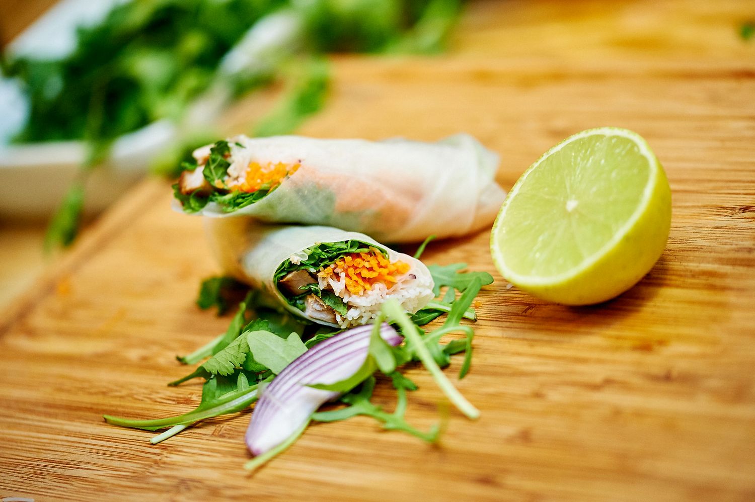 Fresh lime wedges and herbs on a wooden cutting board for food preparation.