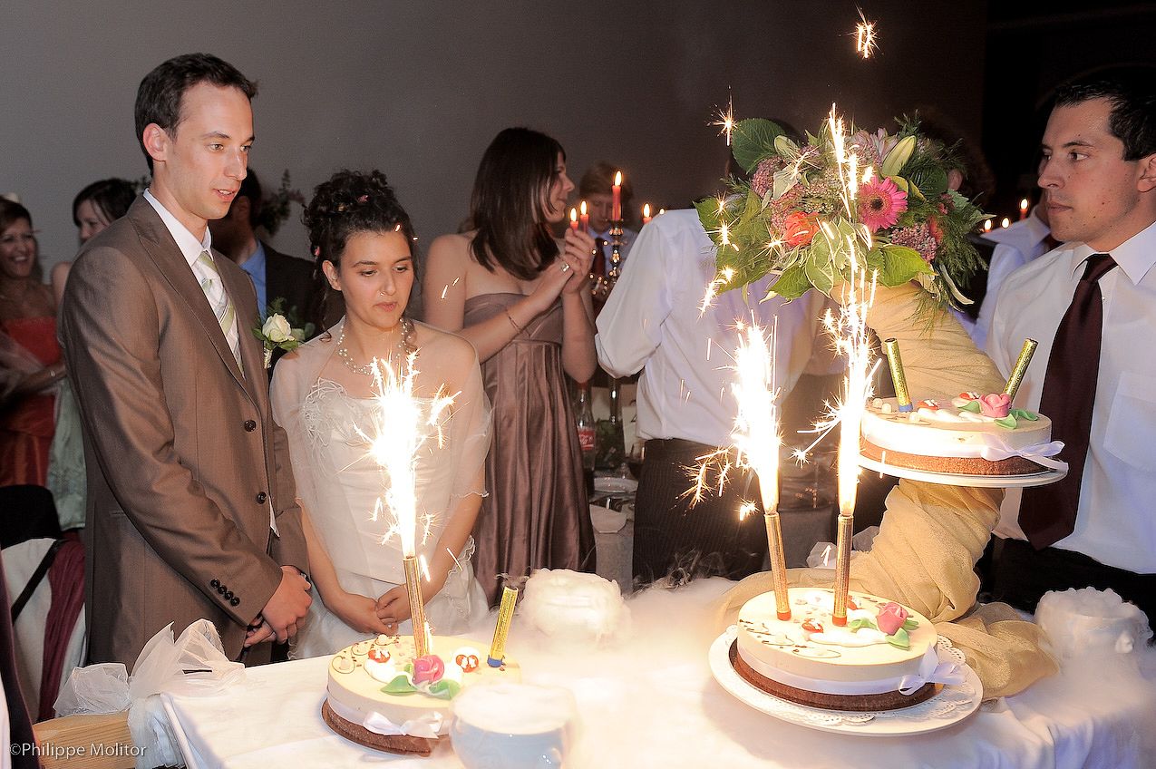 Wedding guests gather around cakes adorned with sparklers at a elegant reception celebration.