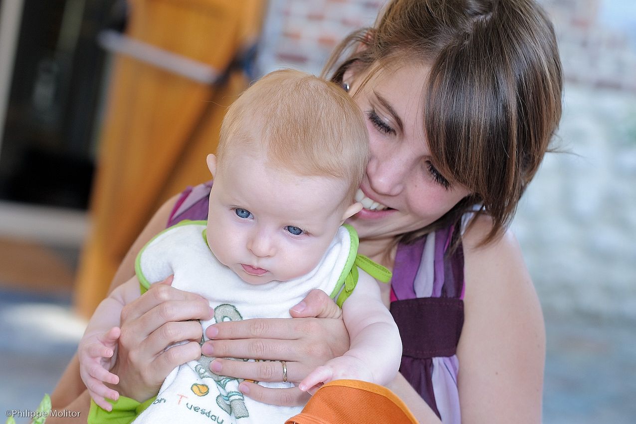Young mother tenderly holding her blue-eyed baby while reading a colorful book together.