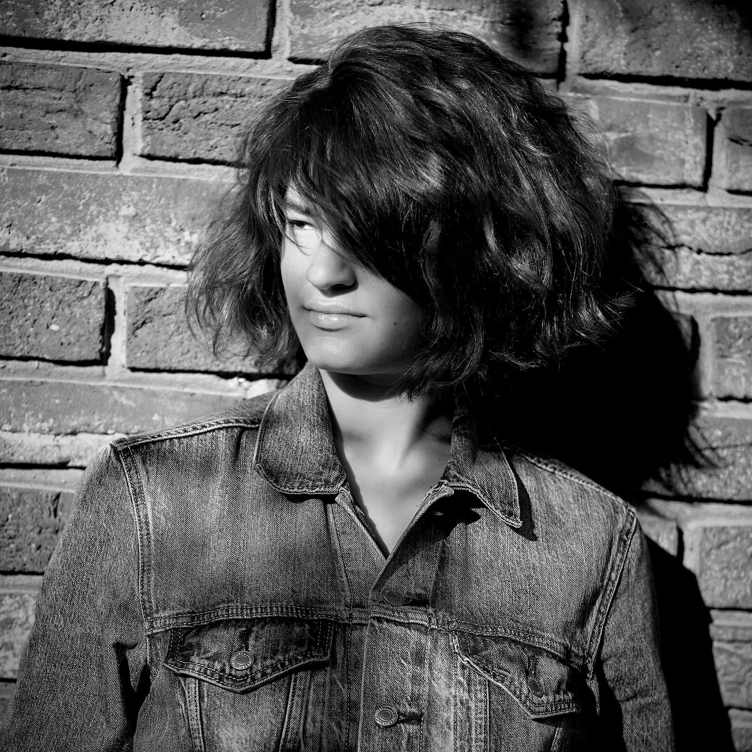 Artistic portraits showing movement in denim jacket against brick wall.