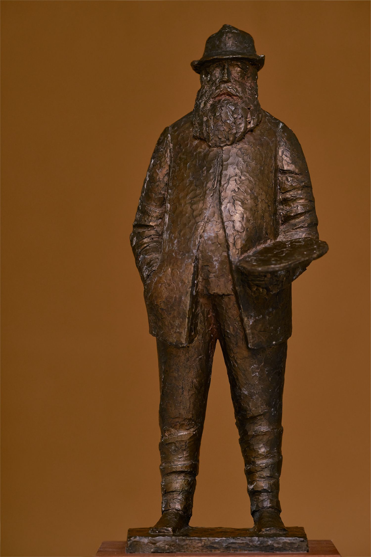 Bronze sculpture series showing figures in traditional workwear against brown background.