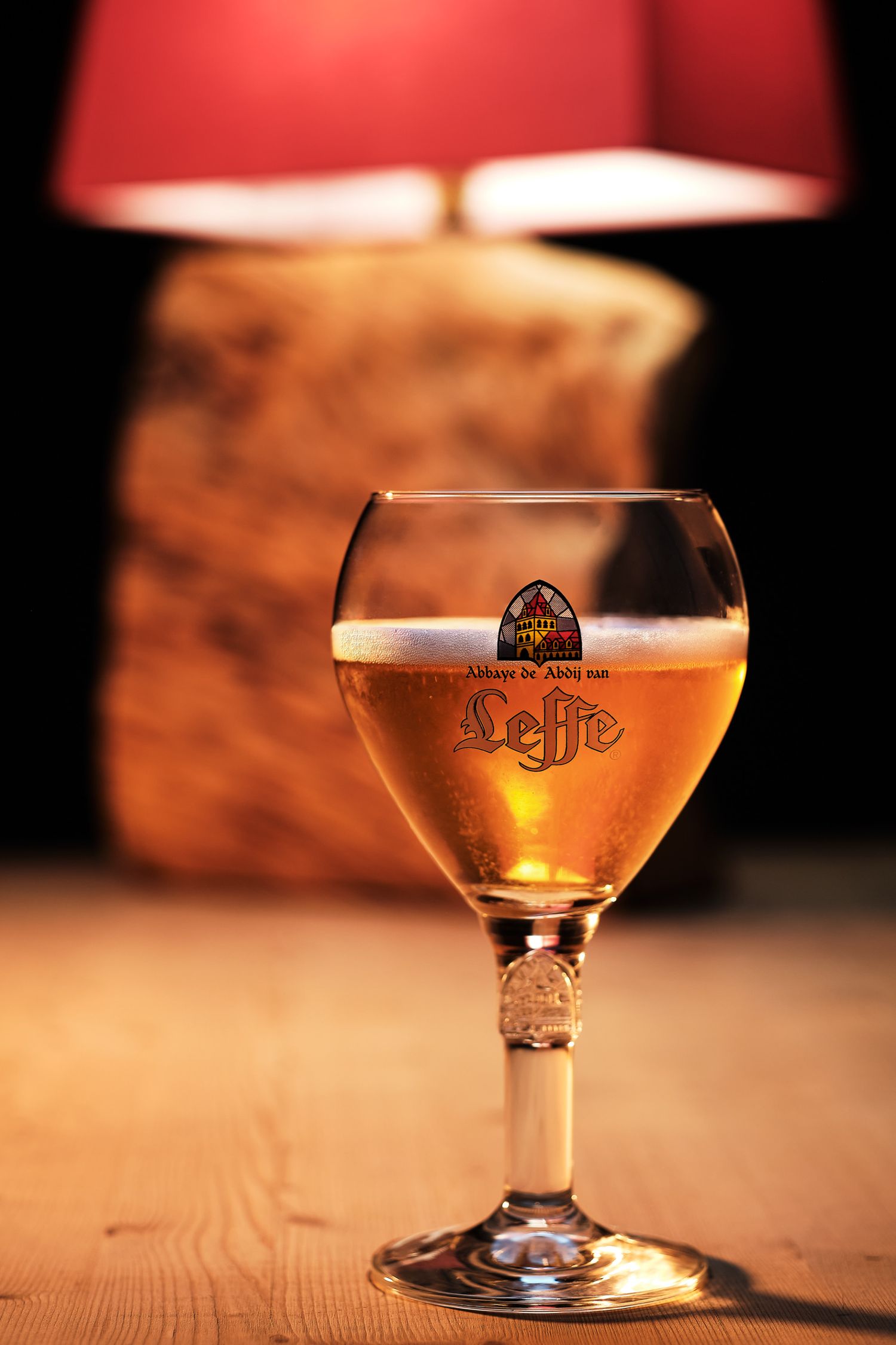 Glass of Leffe beer with perfect foam head captured in warm ambient lighting.