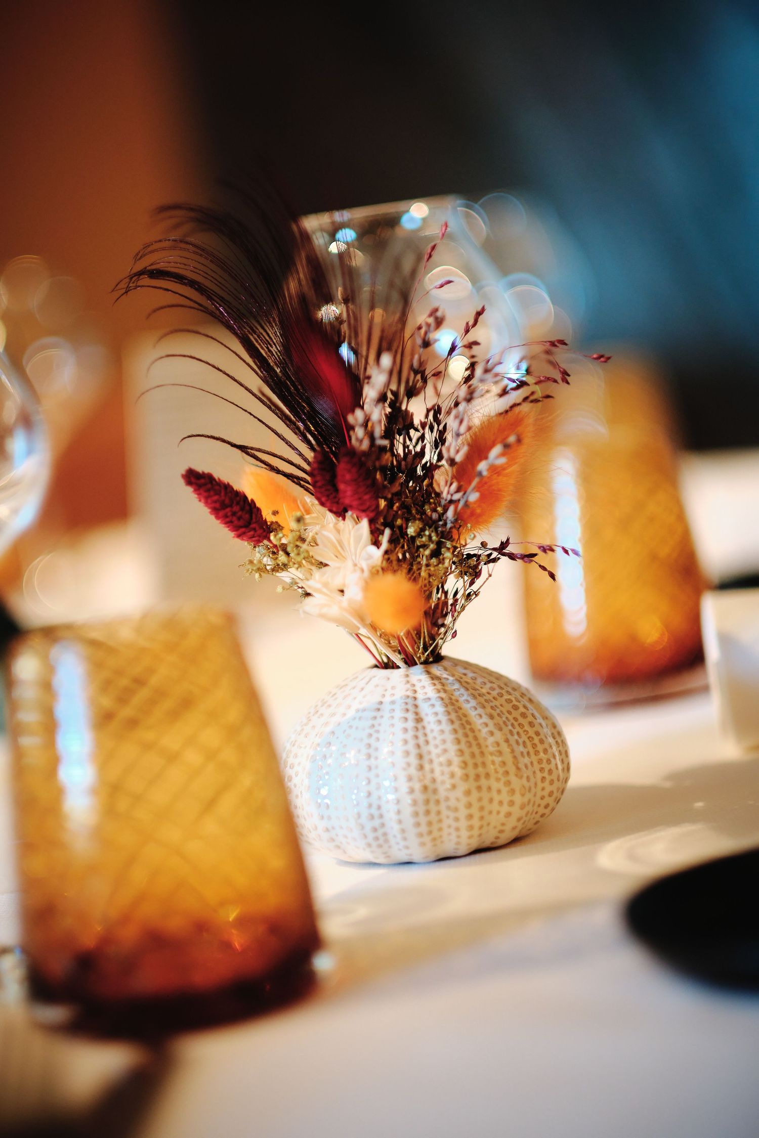 Decorative sea urchin shaped vases with dried flowers arranged on a white tablecloth.