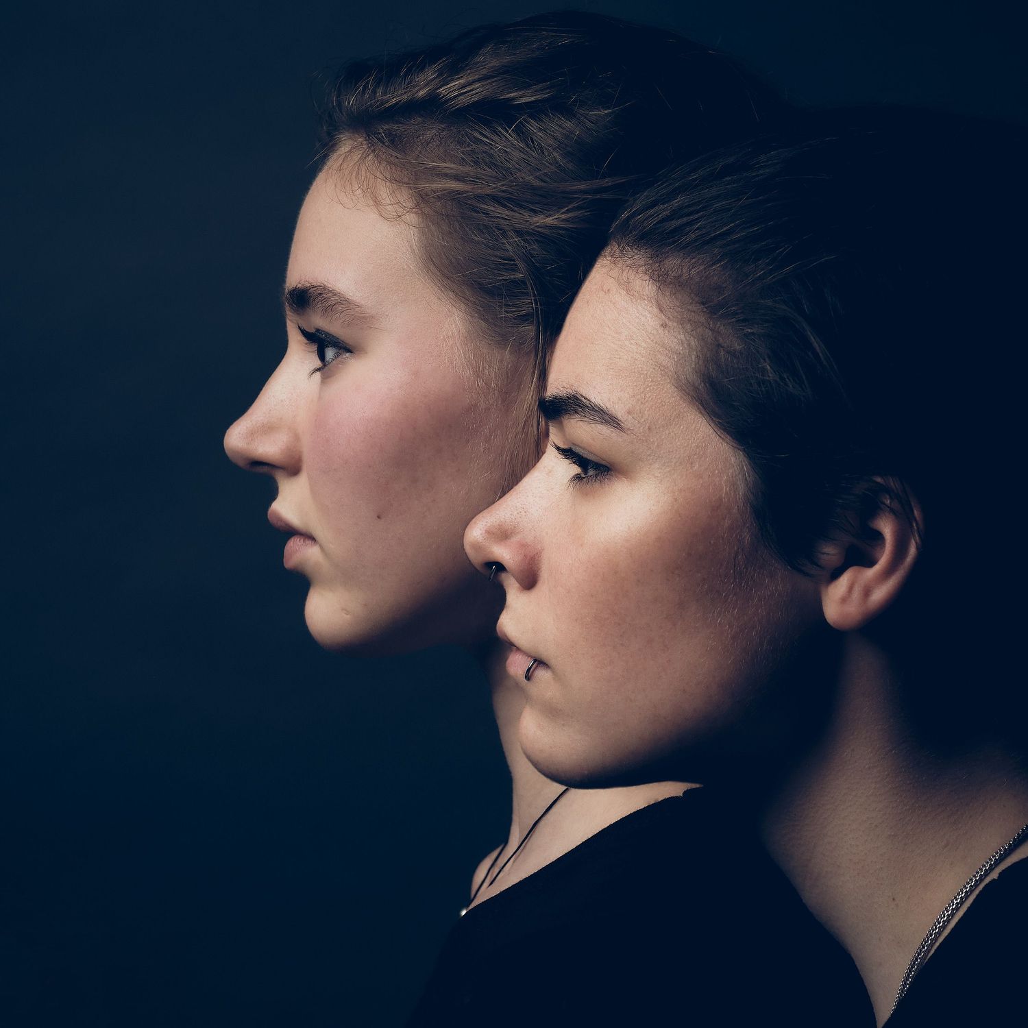 Profile silhouettes in dramatic black and white lighting create an artistic portrait series.