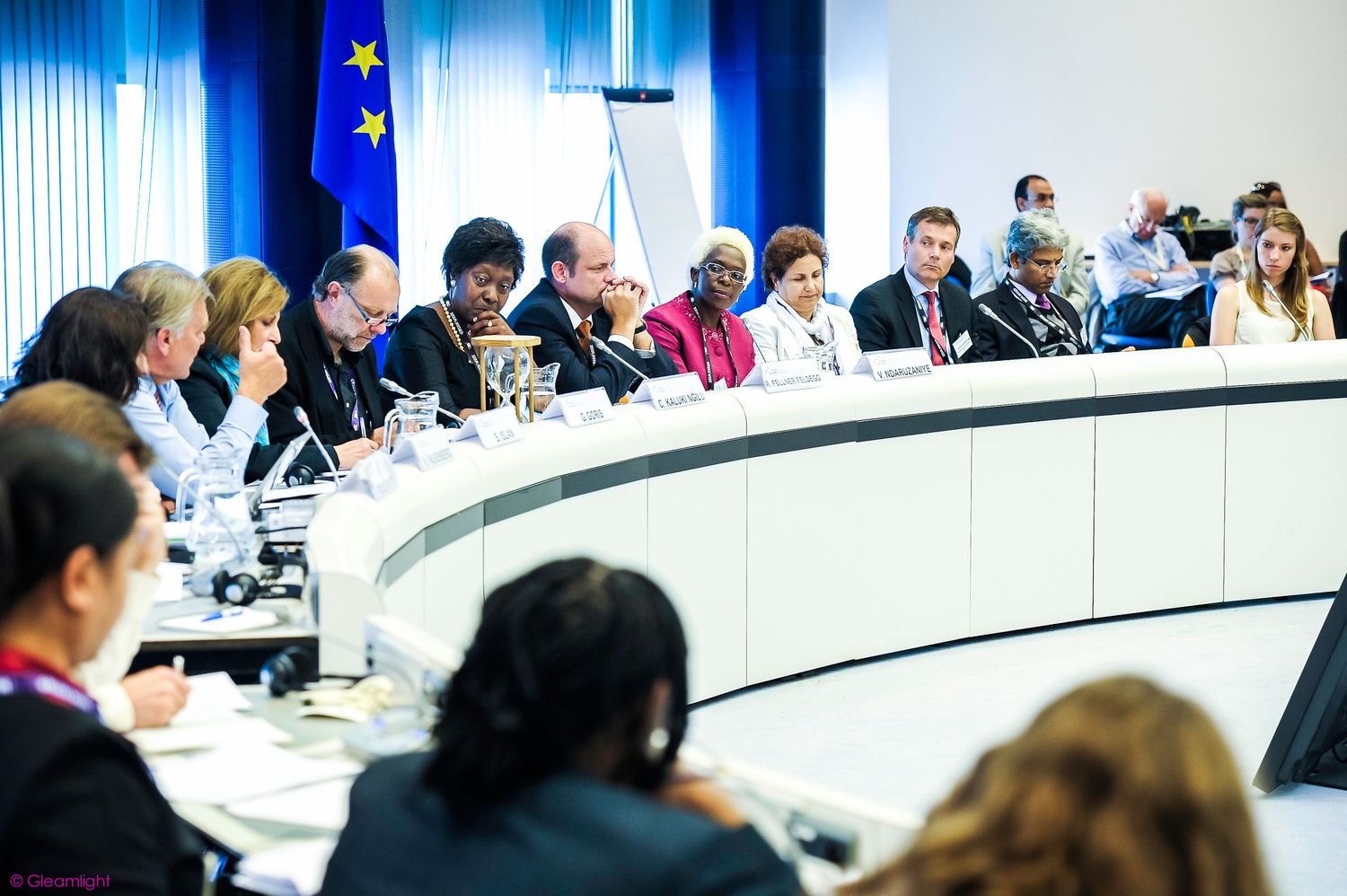 Business professionals seated at a long conference table during a meeting in a modern office setting.