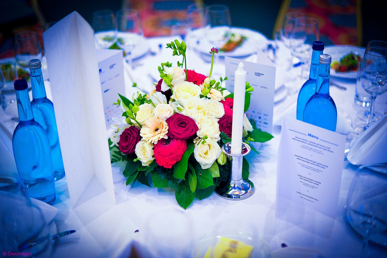 Conference table decorated with floral arrangements and meeting materials in soft lighting.