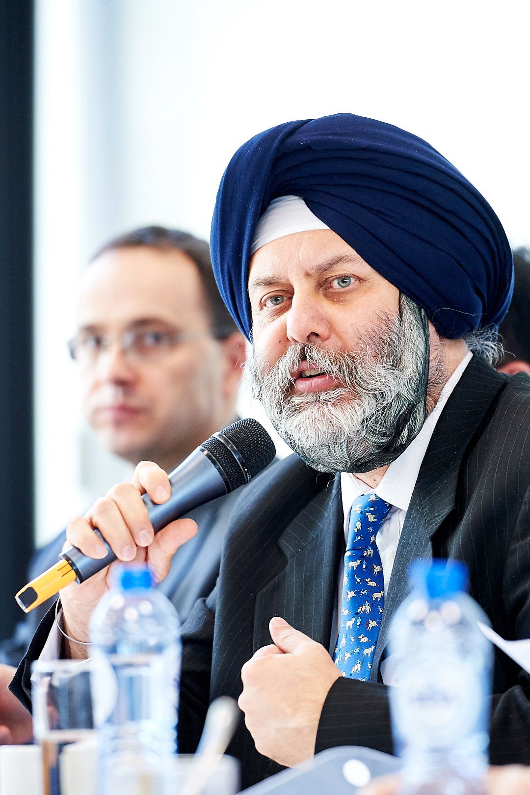Panel speakers at business conference discussing topics with microphones.